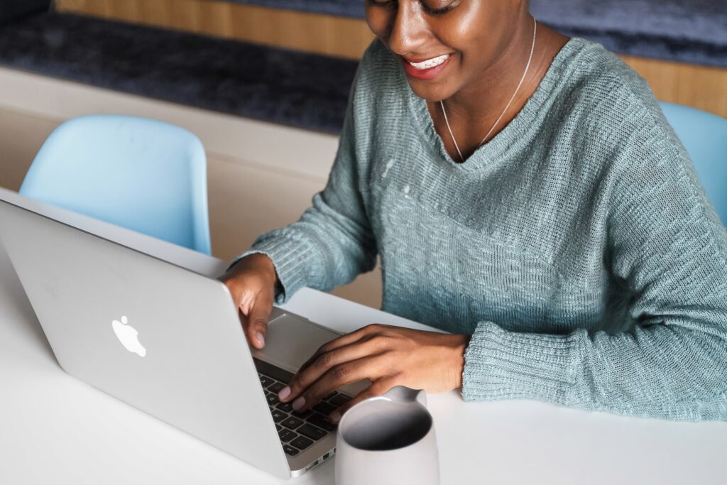 Woman smiling as she optimises her professional background on her Apple Macbook