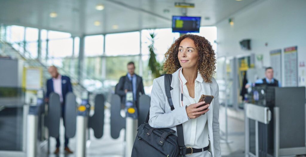 Woman holding a phone and smiling as she walks out of the airport